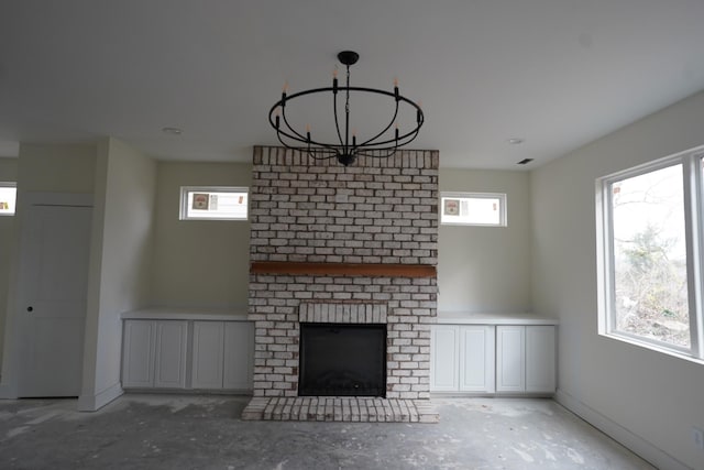 unfurnished living room featuring a chandelier, concrete floors, and a fireplace