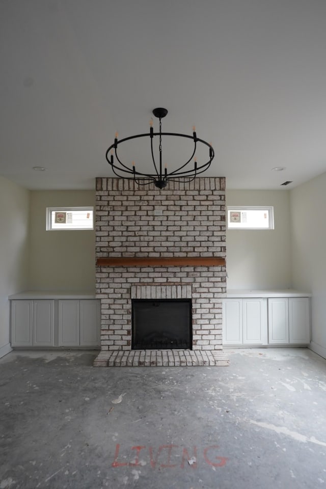 unfurnished living room featuring an inviting chandelier, a wealth of natural light, a fireplace, and concrete flooring