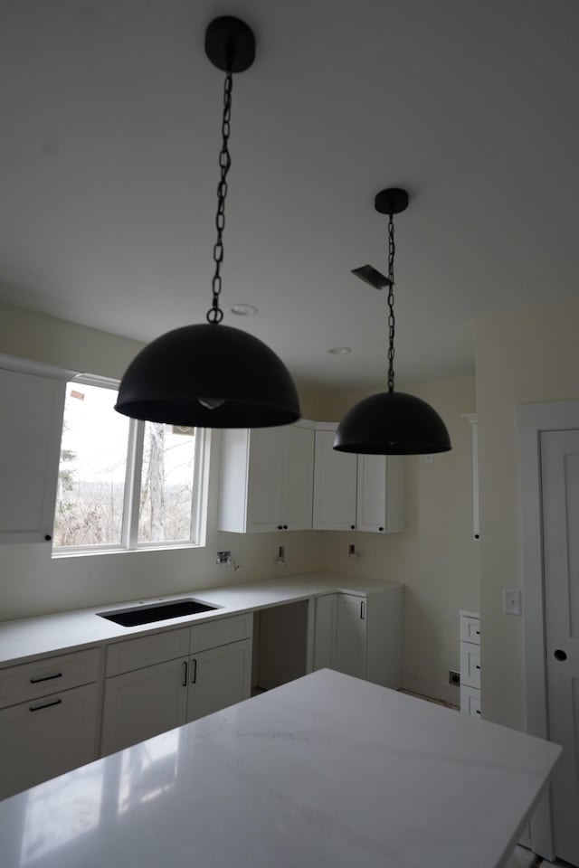 kitchen featuring pendant lighting, cooktop, and white cabinets