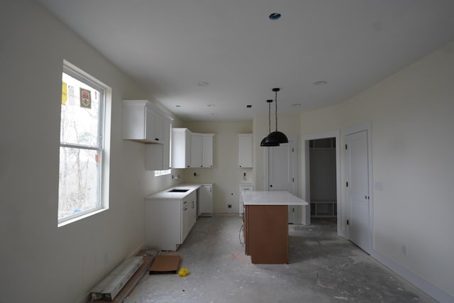 kitchen with decorative light fixtures, a kitchen breakfast bar, a kitchen island, and white cabinets