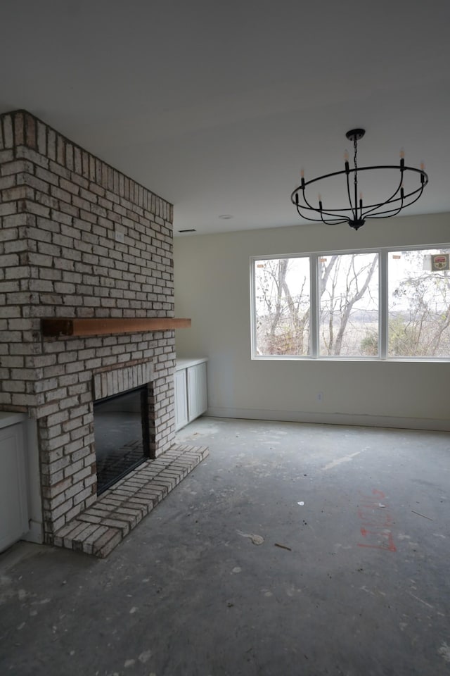 unfurnished living room featuring a brick fireplace and a notable chandelier