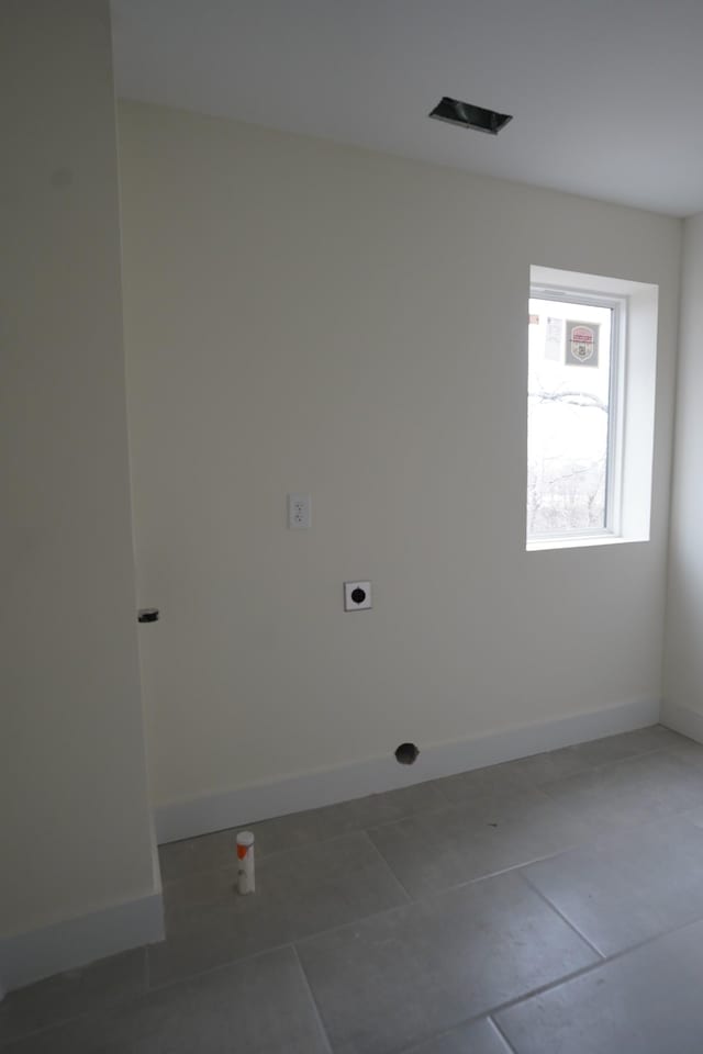 clothes washing area with hookup for an electric dryer and tile patterned floors