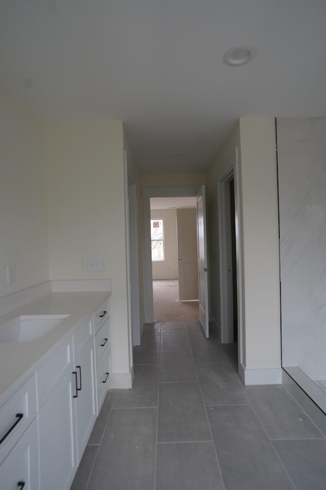 hall with sink and dark tile patterned floors