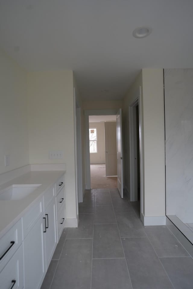 hall with sink and dark tile patterned floors