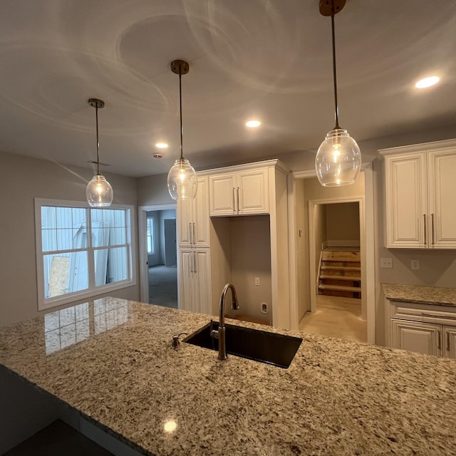 kitchen with sink, hanging light fixtures, and white cabinets