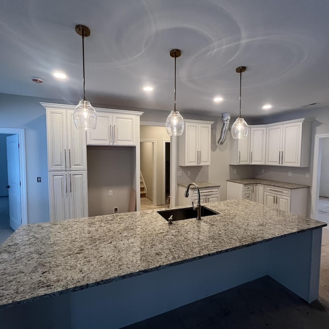 kitchen featuring decorative light fixtures, sink, white cabinets, and light stone countertops