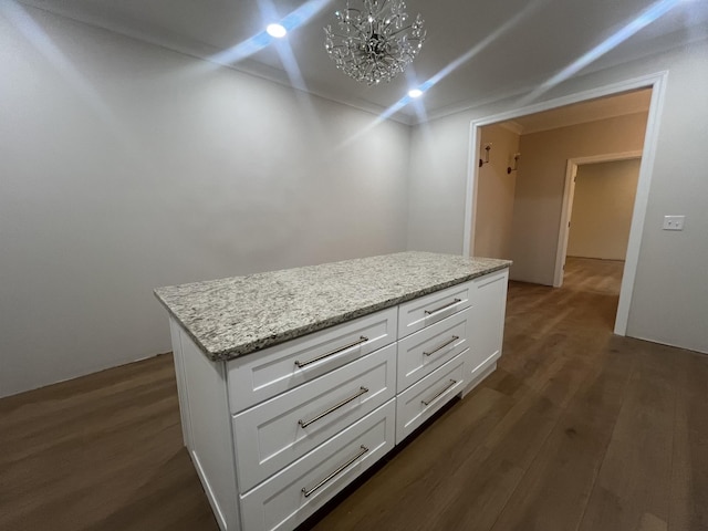 kitchen featuring white cabinets, a center island, dark hardwood / wood-style flooring, a chandelier, and light stone counters