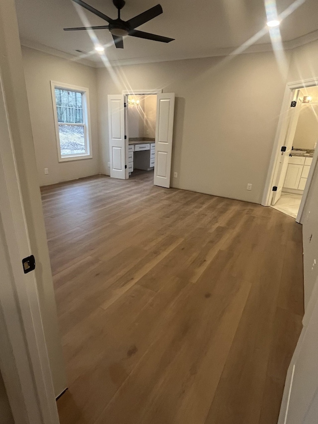 unfurnished living room with ceiling fan, wood-type flooring, and crown molding