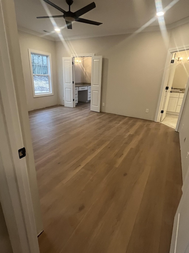 interior space with ensuite bath, wood-type flooring, and ceiling fan