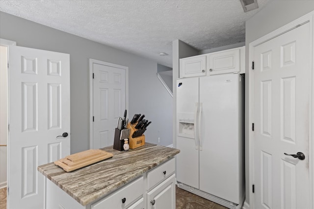 kitchen with white cabinetry, white fridge with ice dispenser, a textured ceiling, and a center island