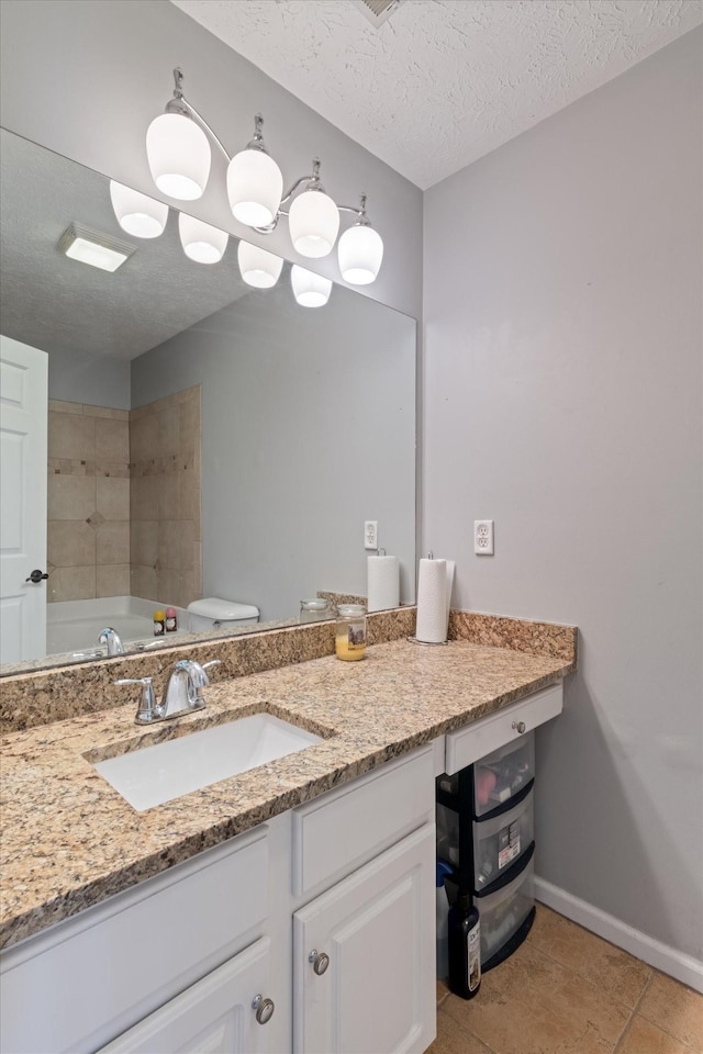 bathroom featuring vanity, a bath, a textured ceiling, tile patterned floors, and toilet