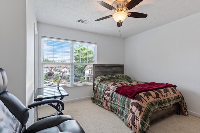 bedroom with ceiling fan, carpet floors, and a textured ceiling