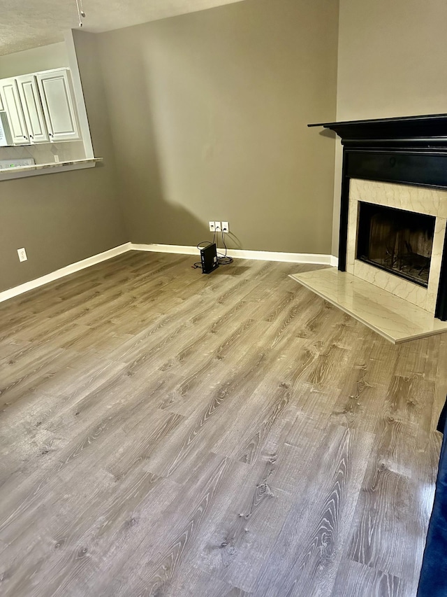 unfurnished living room featuring a tile fireplace and light hardwood / wood-style floors