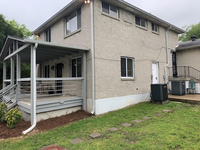 rear view of house with central air condition unit and a lawn