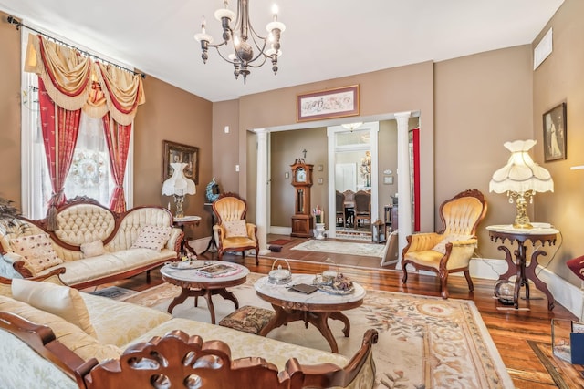 sitting room featuring a chandelier, hardwood / wood-style floors, and decorative columns