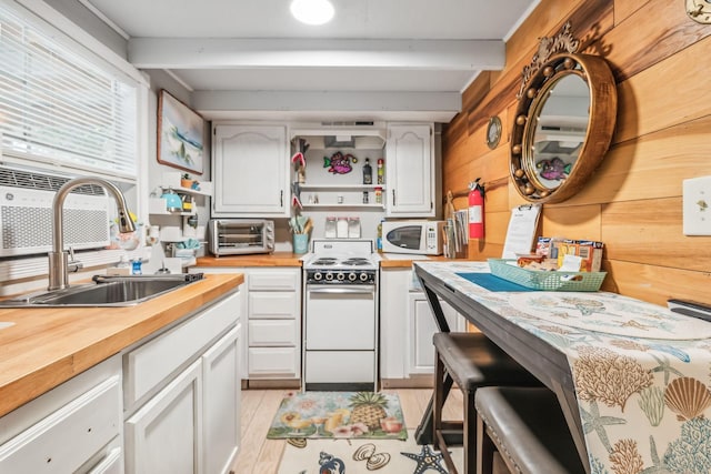 kitchen featuring white cabinetry, wooden walls, sink, and range