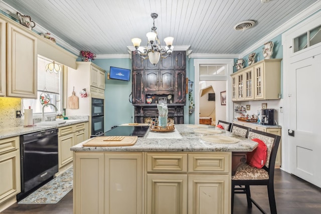 kitchen featuring cream cabinetry, a kitchen breakfast bar, a center island, and black appliances