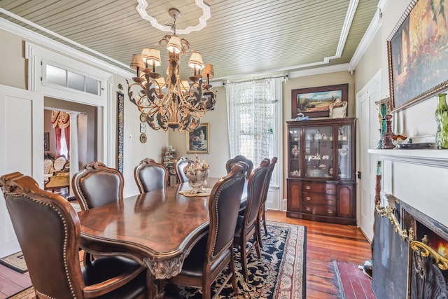 dining area with wooden ceiling, hardwood / wood-style flooring, an inviting chandelier, and ornamental molding