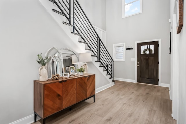 entrance foyer featuring a towering ceiling and light hardwood / wood-style flooring