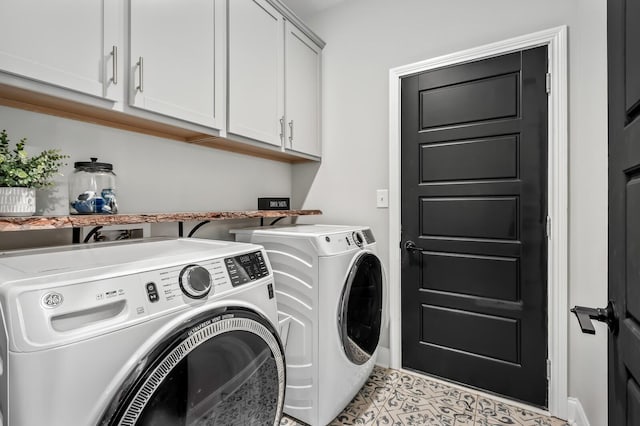 clothes washing area with cabinets, light tile patterned floors, and washer and clothes dryer