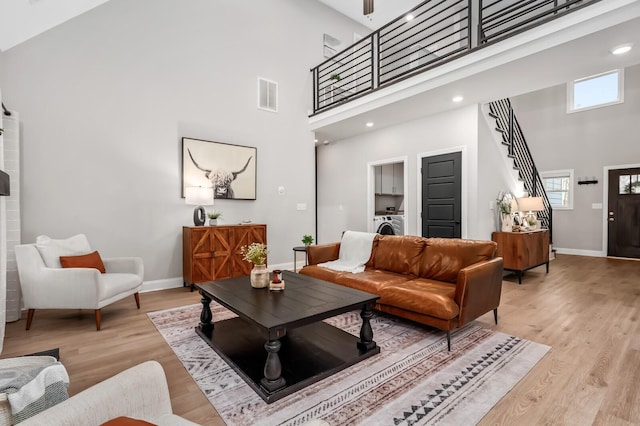 living room featuring a towering ceiling, a wealth of natural light, and light hardwood / wood-style flooring