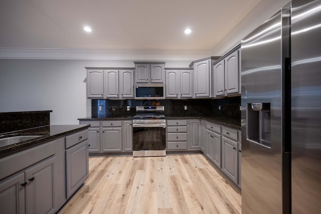 kitchen with gray cabinets, stainless steel appliances, and dark stone counters