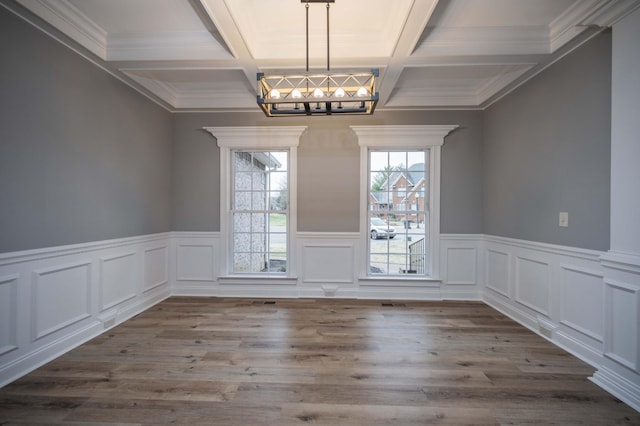 unfurnished dining area with a chandelier, hardwood / wood-style flooring, a wealth of natural light, and coffered ceiling