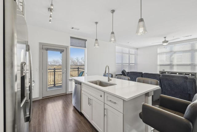 kitchen with a kitchen island with sink, sink, decorative light fixtures, white cabinetry, and stainless steel appliances