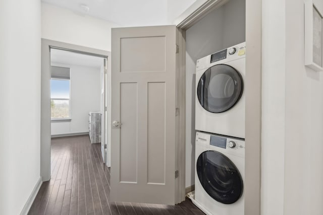 laundry area featuring stacked washer / drying machine and dark wood-type flooring