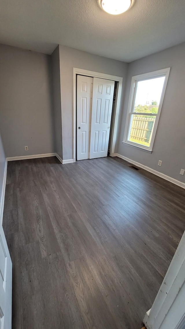 unfurnished bedroom with a textured ceiling and dark wood-type flooring