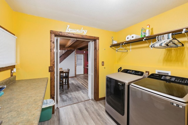 laundry room with independent washer and dryer, a textured ceiling, and light hardwood / wood-style flooring