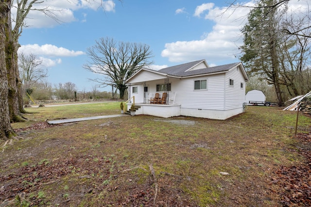 view of front of house with covered porch, a storage shed, and a front yard