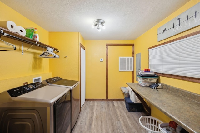 laundry area featuring washer and dryer, a textured ceiling, and light wood-type flooring