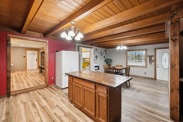 kitchen with a center island, hanging light fixtures, an inviting chandelier, butcher block countertops, and white fridge