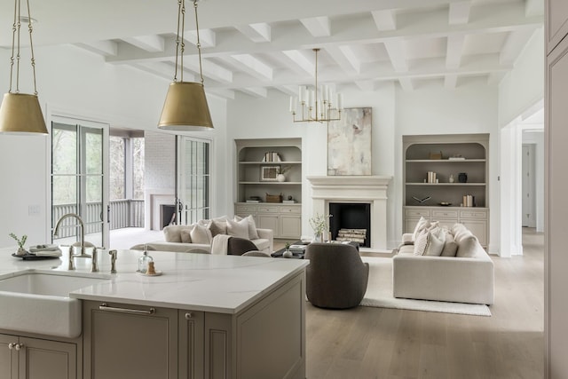 living room featuring beam ceiling, light hardwood / wood-style floors, built in features, and sink