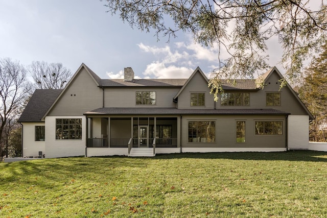 rear view of house featuring a sunroom and a lawn