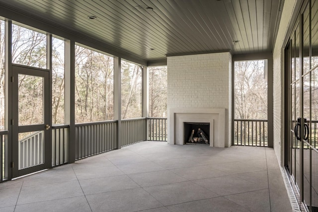 unfurnished sunroom featuring a large fireplace and wood ceiling