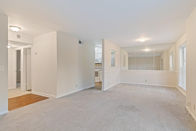 empty room with baseboards, visible vents, and light carpet