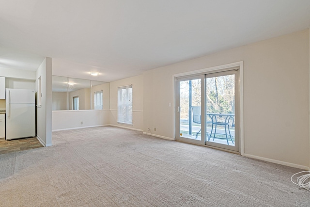 unfurnished living room with baseboards and light carpet