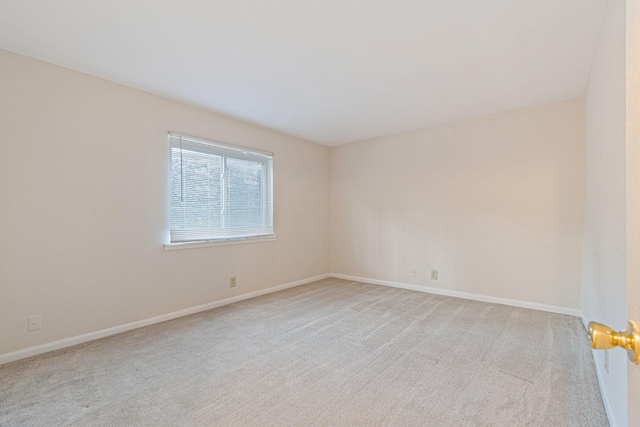 spare room with light colored carpet and baseboards