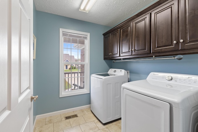 washroom with separate washer and dryer, light tile patterned flooring, cabinets, and a textured ceiling