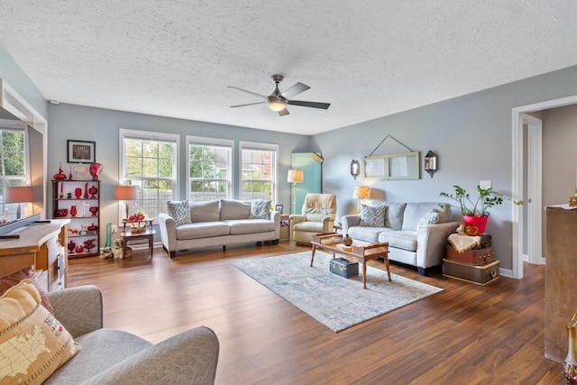 living room with a textured ceiling, dark hardwood / wood-style flooring, and ceiling fan