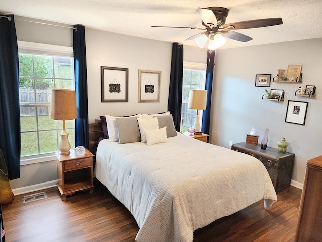 bedroom with ceiling fan, dark hardwood / wood-style floors, and a textured ceiling