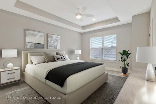 bedroom with hardwood / wood-style flooring, ceiling fan, and a raised ceiling