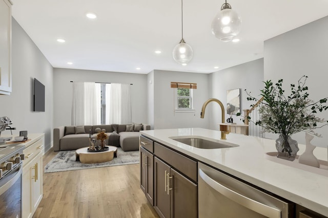 kitchen featuring dishwasher, sink, a healthy amount of sunlight, and decorative light fixtures