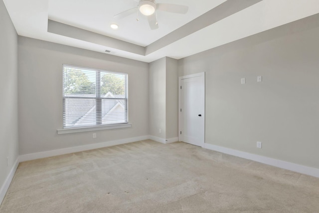 carpeted empty room featuring a raised ceiling and ceiling fan