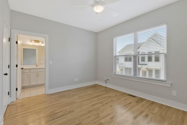 unfurnished bedroom featuring ensuite bath, light hardwood / wood-style floors, and ceiling fan