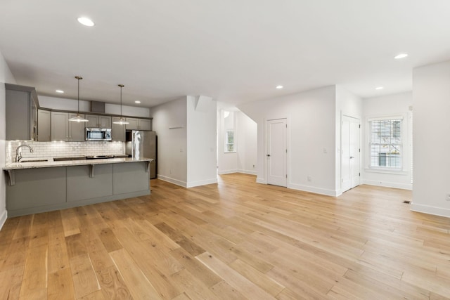 kitchen featuring gray cabinetry, pendant lighting, sink, kitchen peninsula, and stainless steel appliances