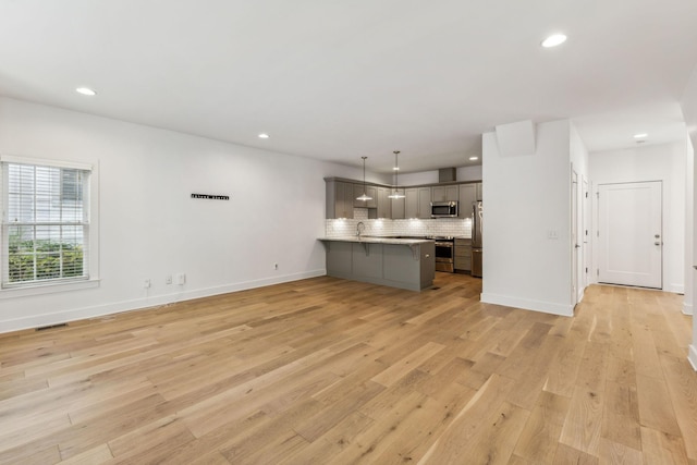 unfurnished living room featuring sink and light hardwood / wood-style floors