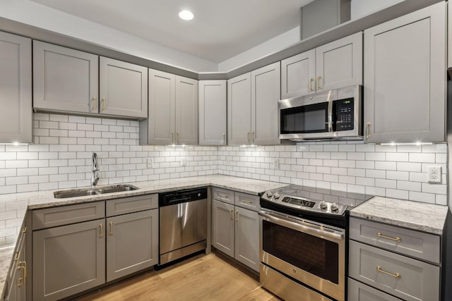 kitchen with tasteful backsplash, gray cabinetry, stainless steel appliances, and light hardwood / wood-style floors